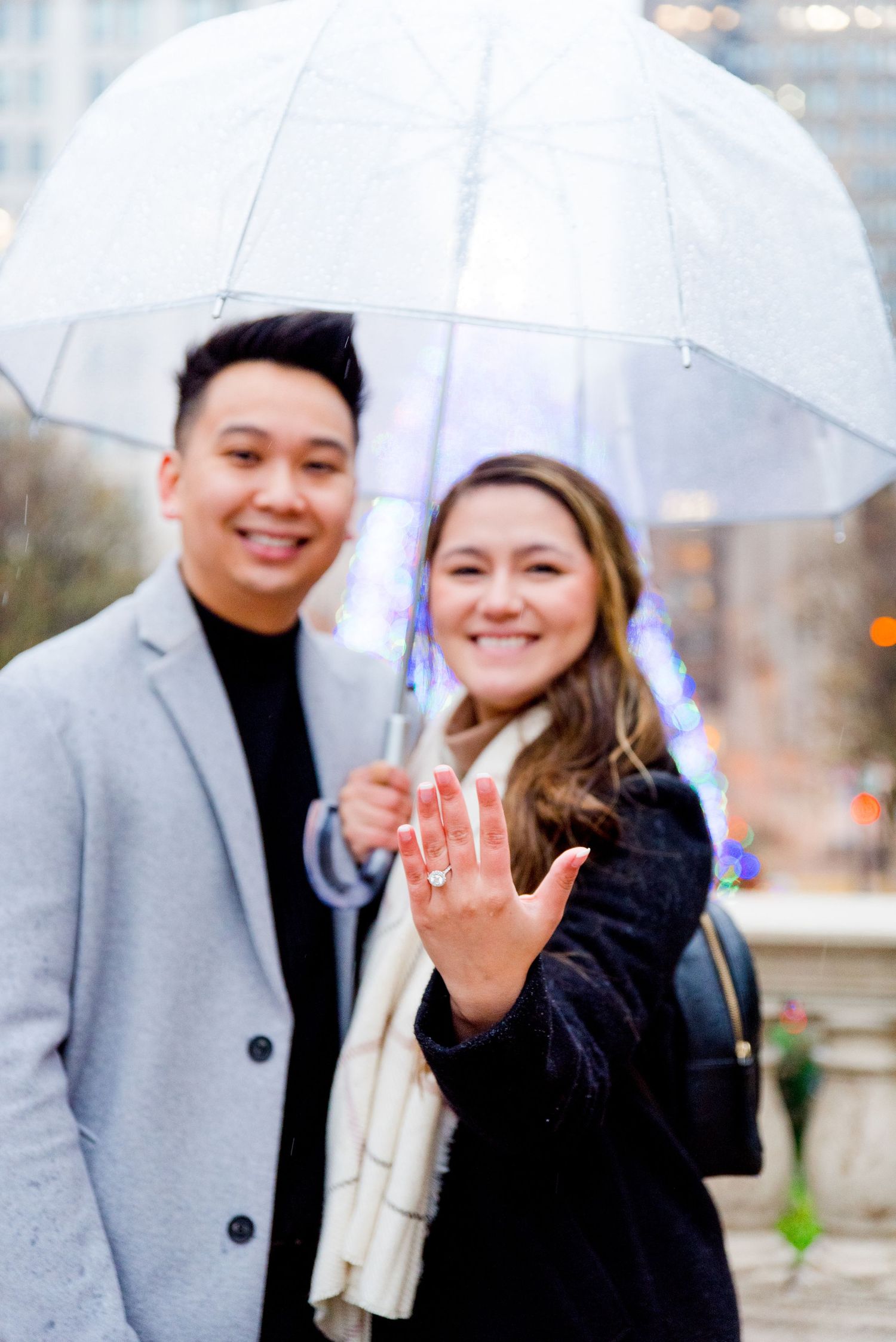 couple hugging under clear umbrella in front of Millennium Park Christmas Tree