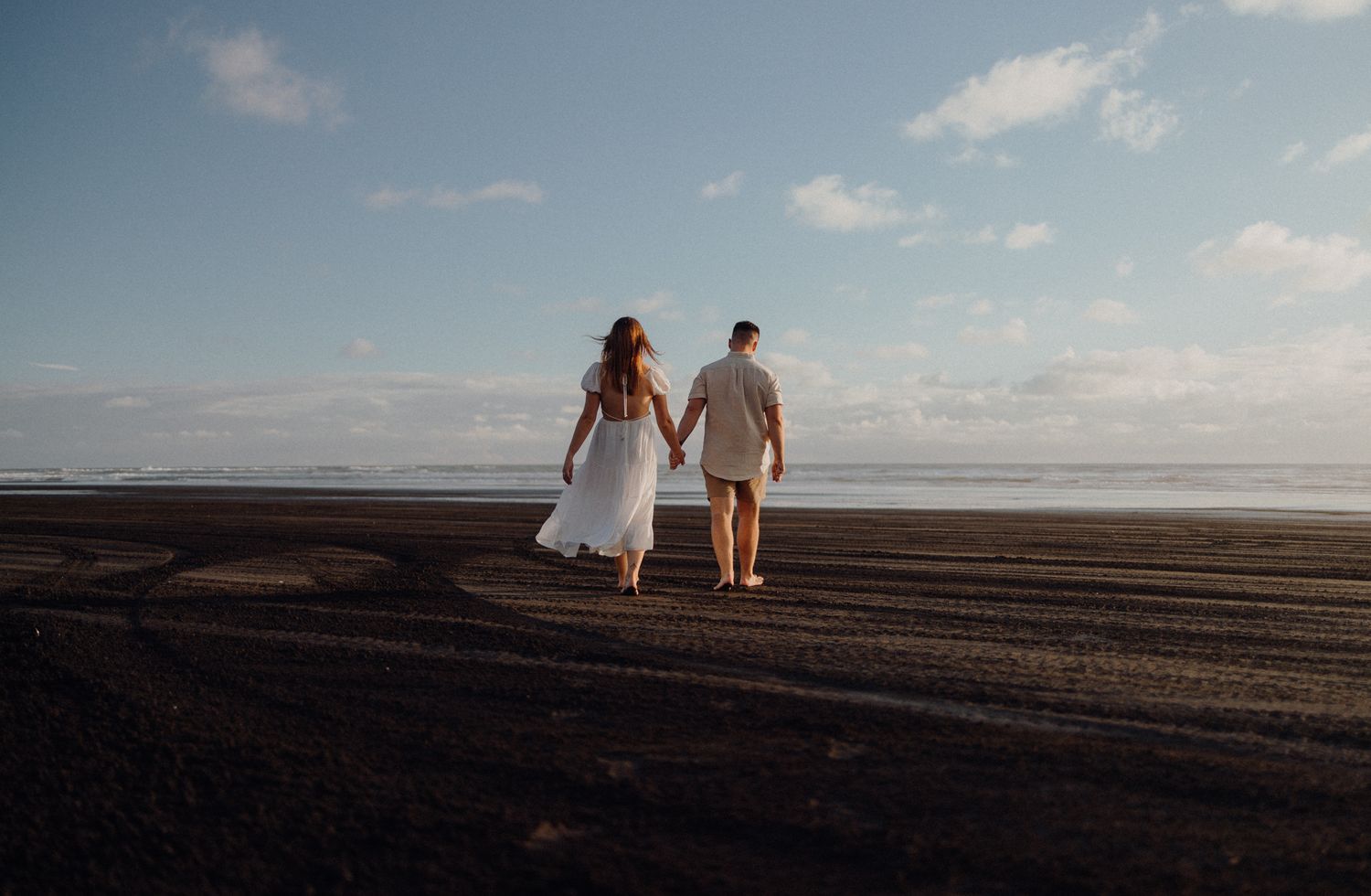 Lovers walking in Karioitahi Beach for their engagement shoot with Apertured Media-Auckland Wedding Photographer