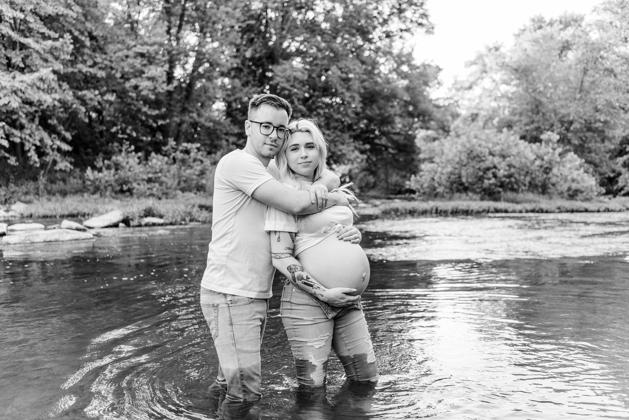 Casual maternity photos in jeans and white shirt with tattoos in stream in Zelienople, Pennsylvania