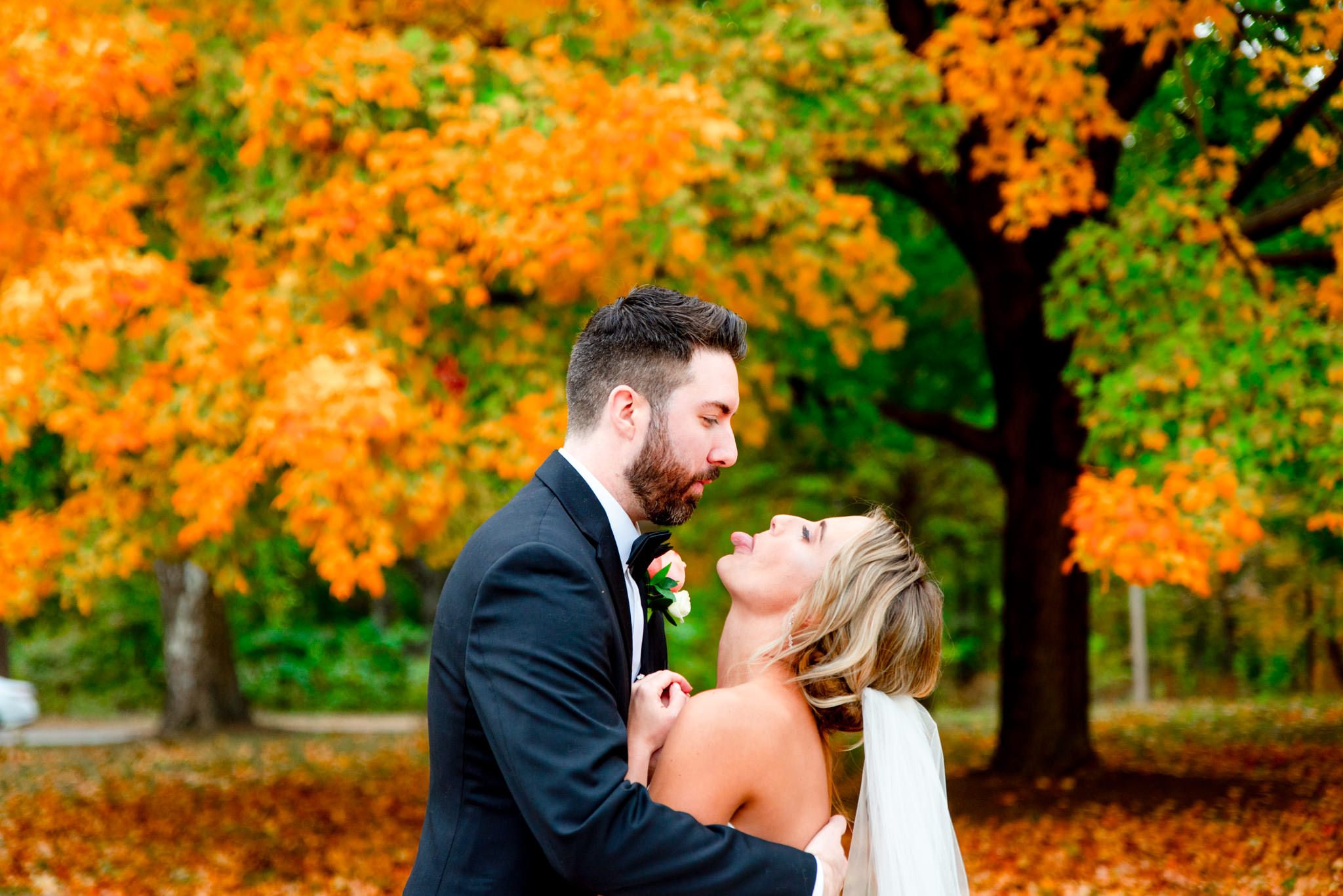 bride sticking tongue out at groom during fall wedding pictures in STL Forest Park
