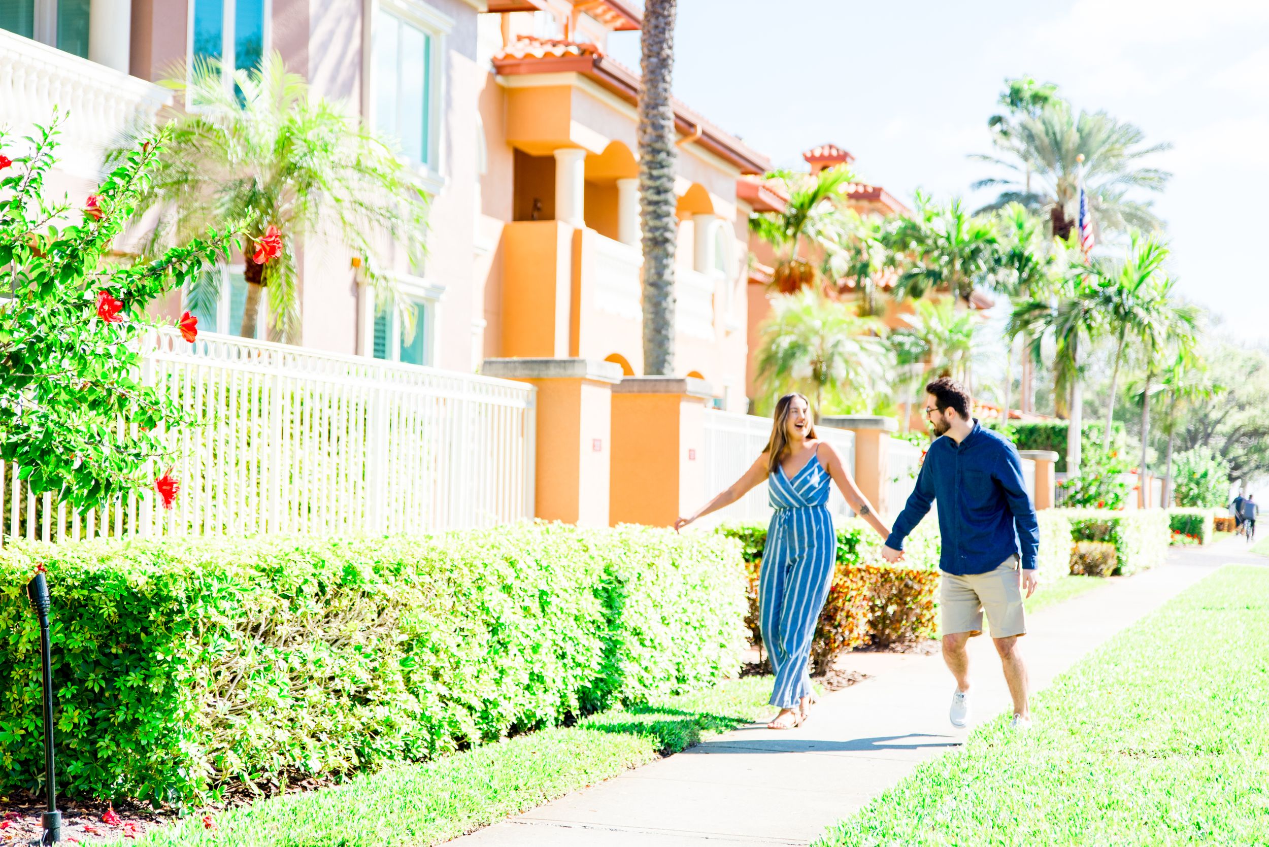 young couple in blue outfits walking and laughing at Vinoy Park St Pete engagement photos
