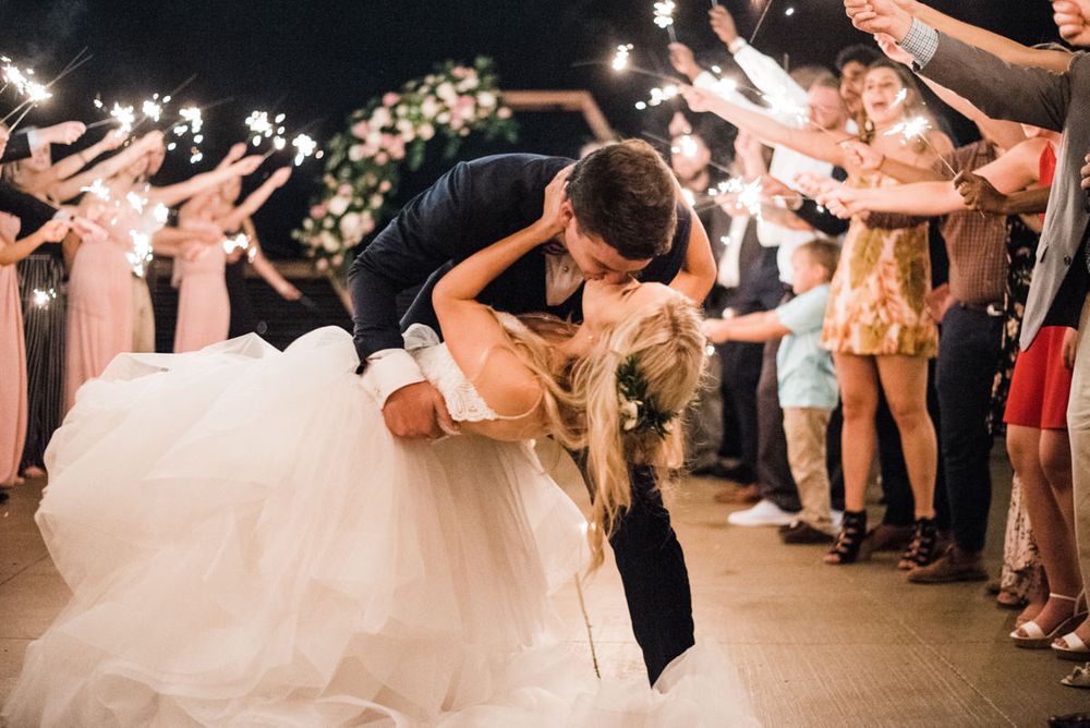 bride and groom dip kissing during sparkler exit