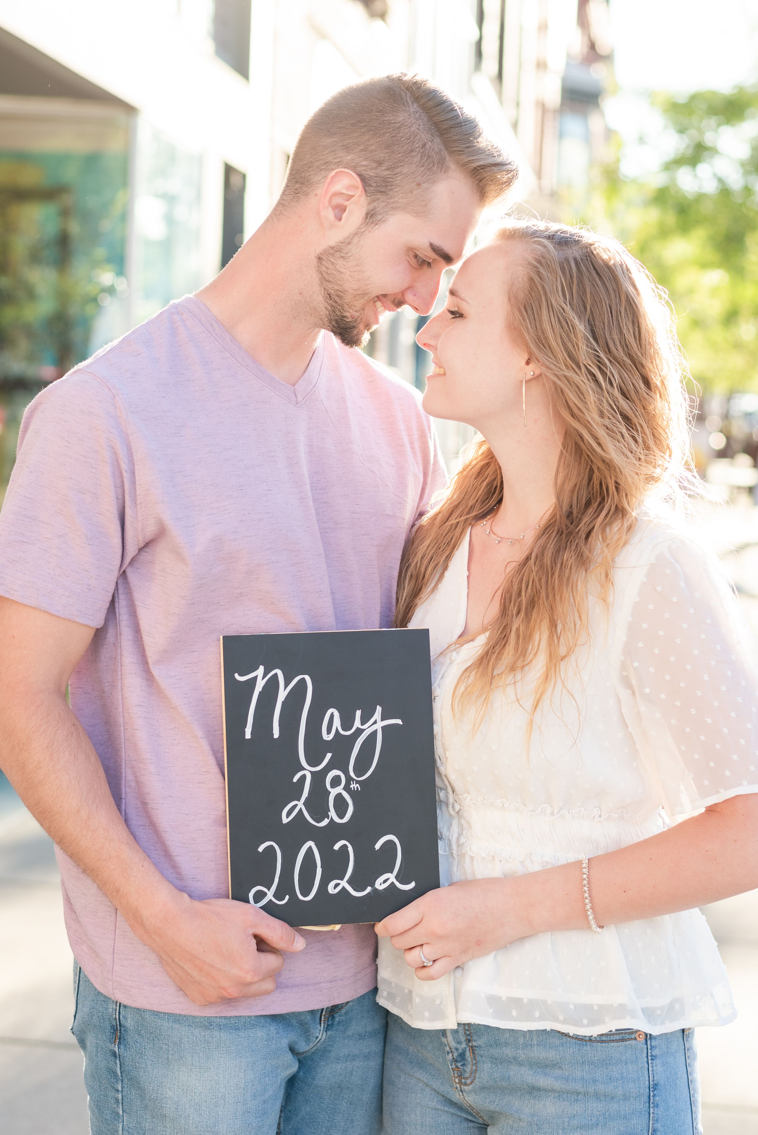 Couple holding save the date sign in sunlight for engagement in Franklin Pennsylvania