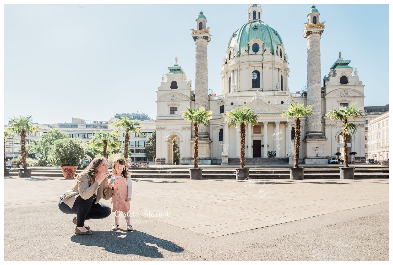 Mother blowing bubbles to toddler in Charles church in Vienna Austria