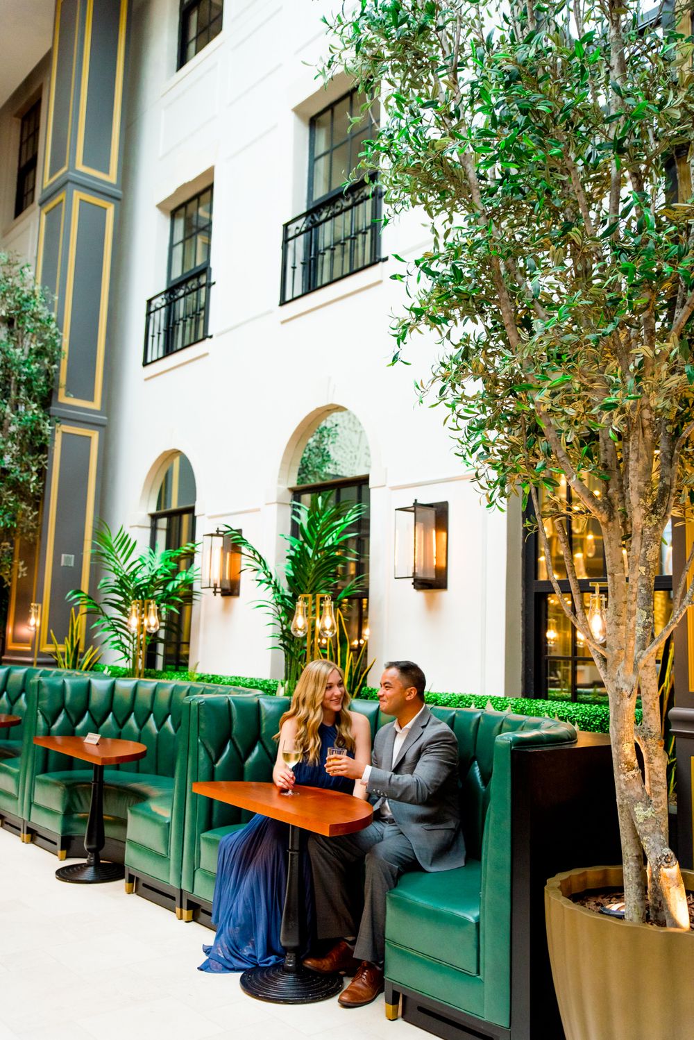 man and woman sit in green booth at Lytle Park Hotel for their engagement pictures