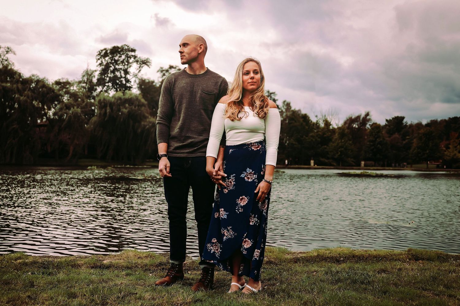 A couple standing together by a lakeside during golden hour.