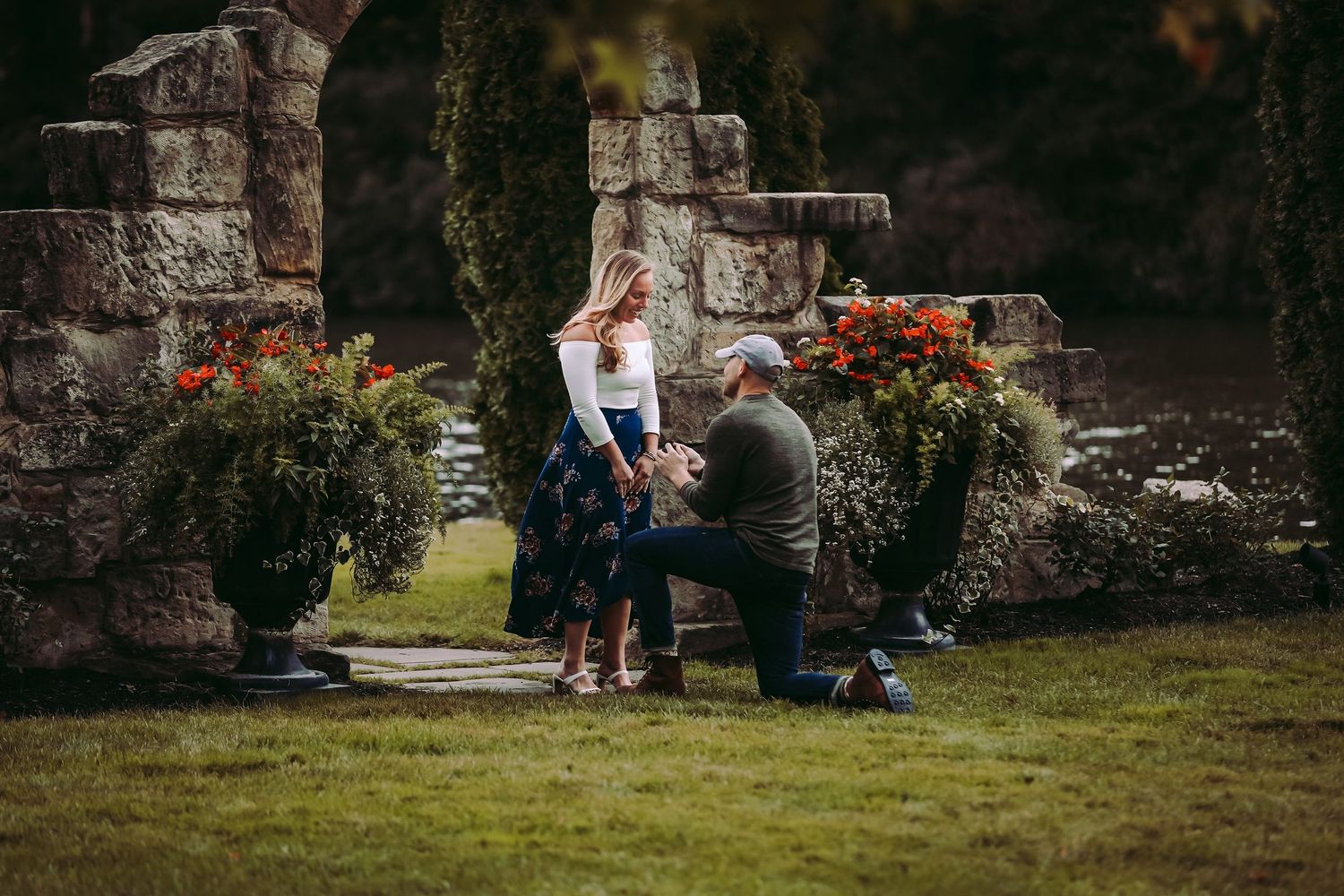 A marriage proposal moment at a scenic stone garden with flowers.