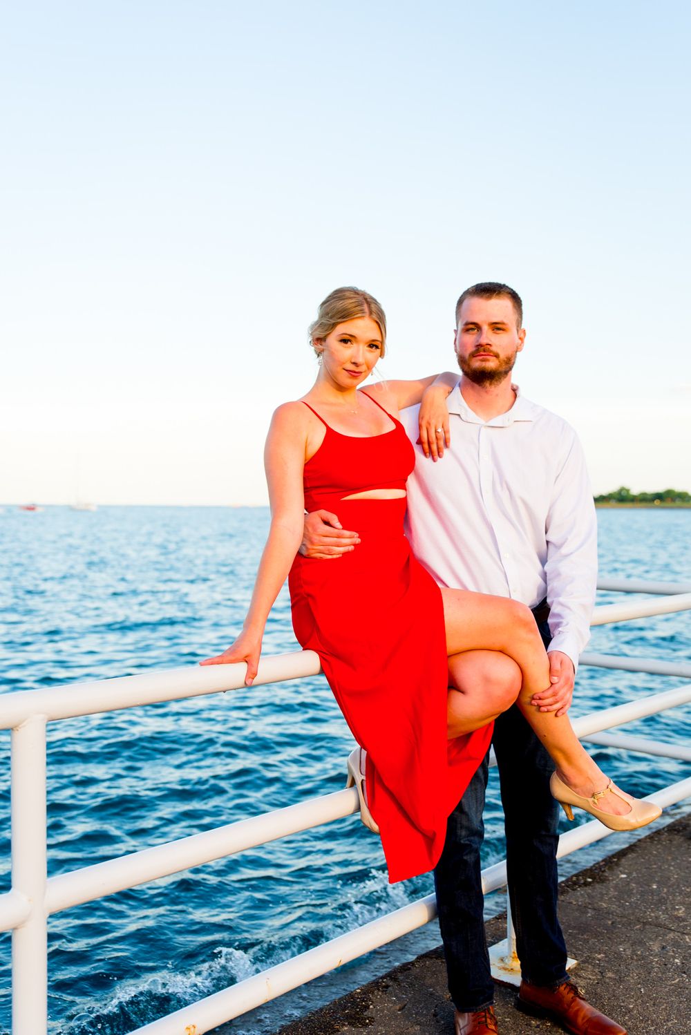 woman in red dress sitting on railing at Chicago lakefront trail at sunset