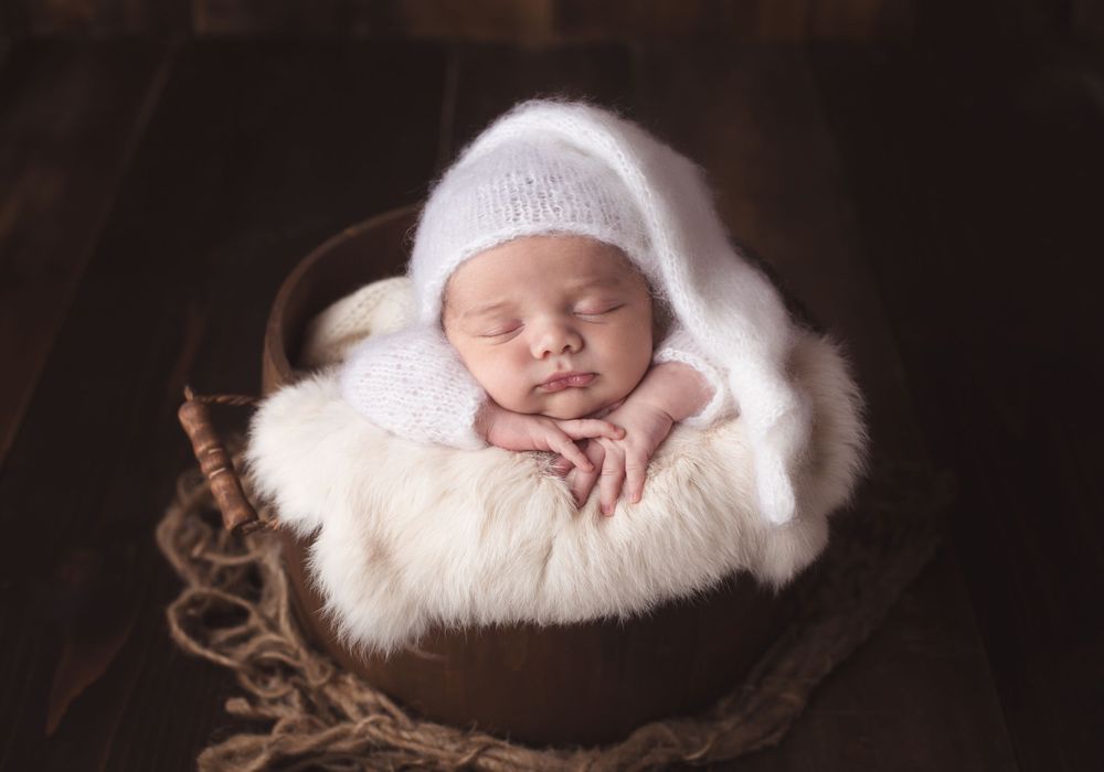 Newborn baby posed in bucket by taken by newborn photographer in Penticton