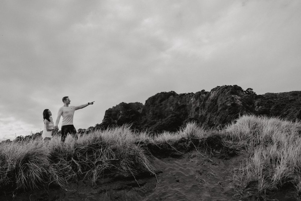 Black and white photo of two people standing on a hilltop overlooking the landscape.