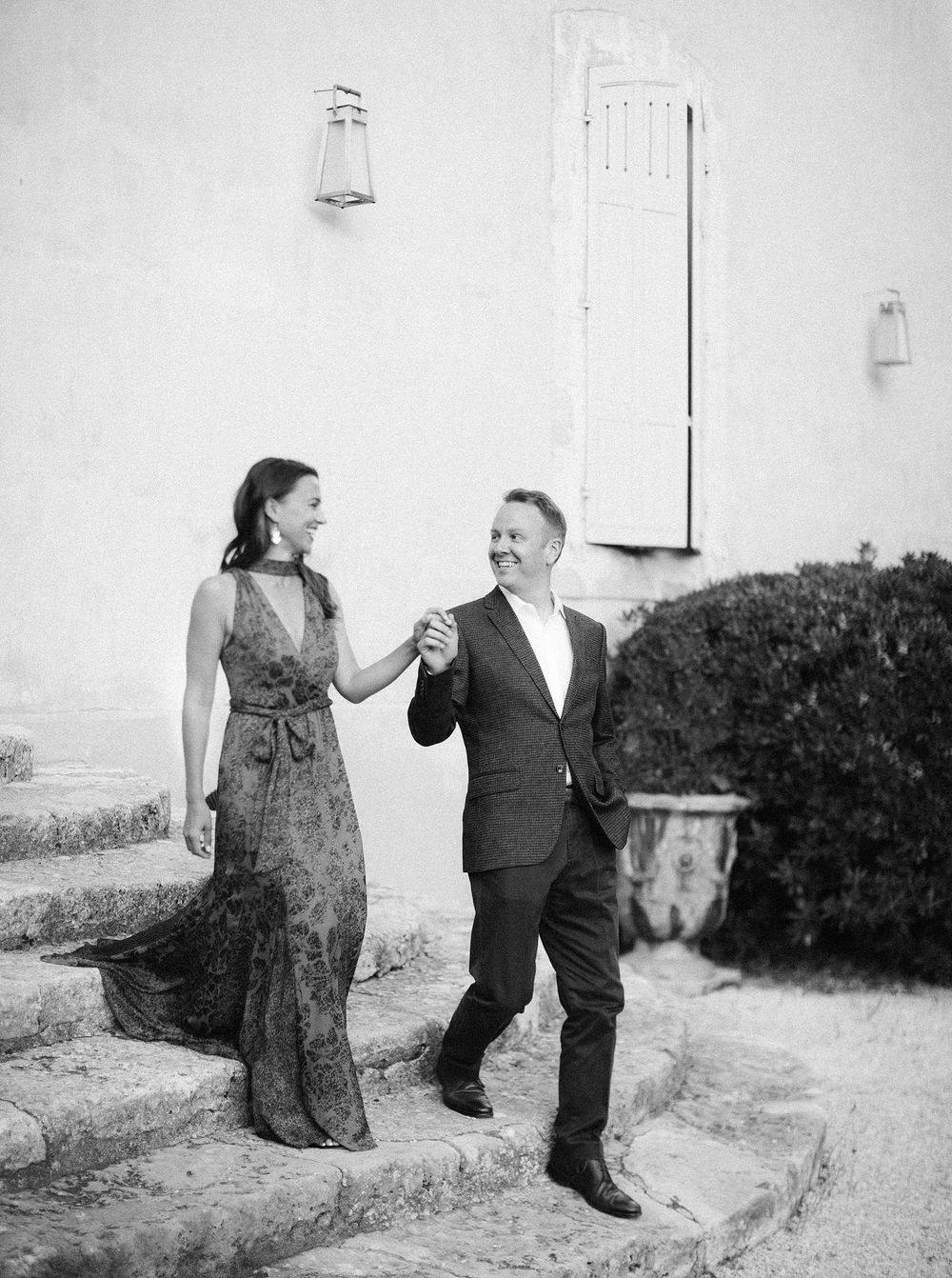 Newlyweds elegantly descend stairs at La Bastide de Ganay, Provence, with a stunning building in the backdrop.
