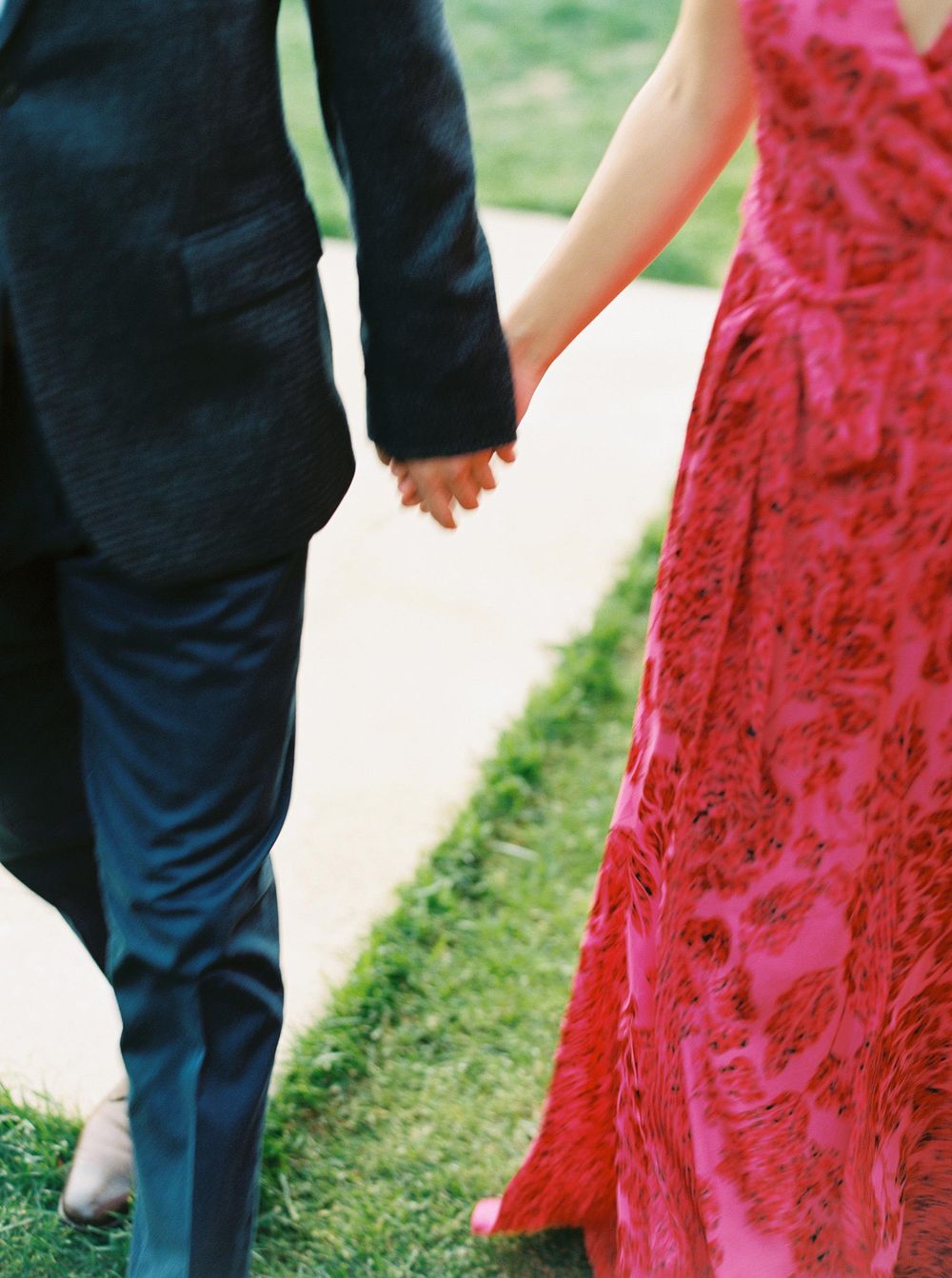 Newlyweds in red dresses, clasping hands as they celebrate their wedding.