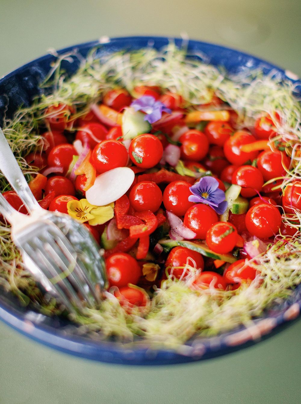 A bowl of tomato salad with a fork and knife, ready to be enjoyed.