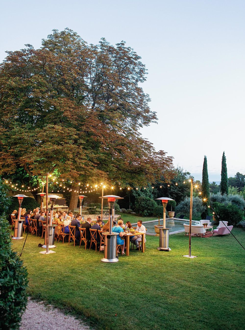 People enjoying a welcome dinner at La Bastide de Ganay, Provence, seated at tables arranged al fresco.