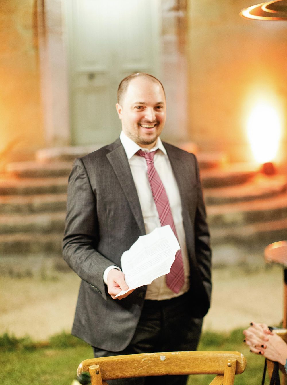 An elegant man in a suit and tie presenting a speech during a welcome dinner.