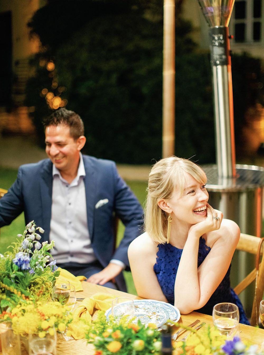 Guests at a welcome dinner: a couple seated at a table adorned with flowers.