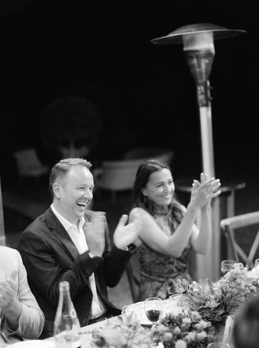 A monochrome image of a bride and groom seated at a dinner table, enjoying a romantic meal together.