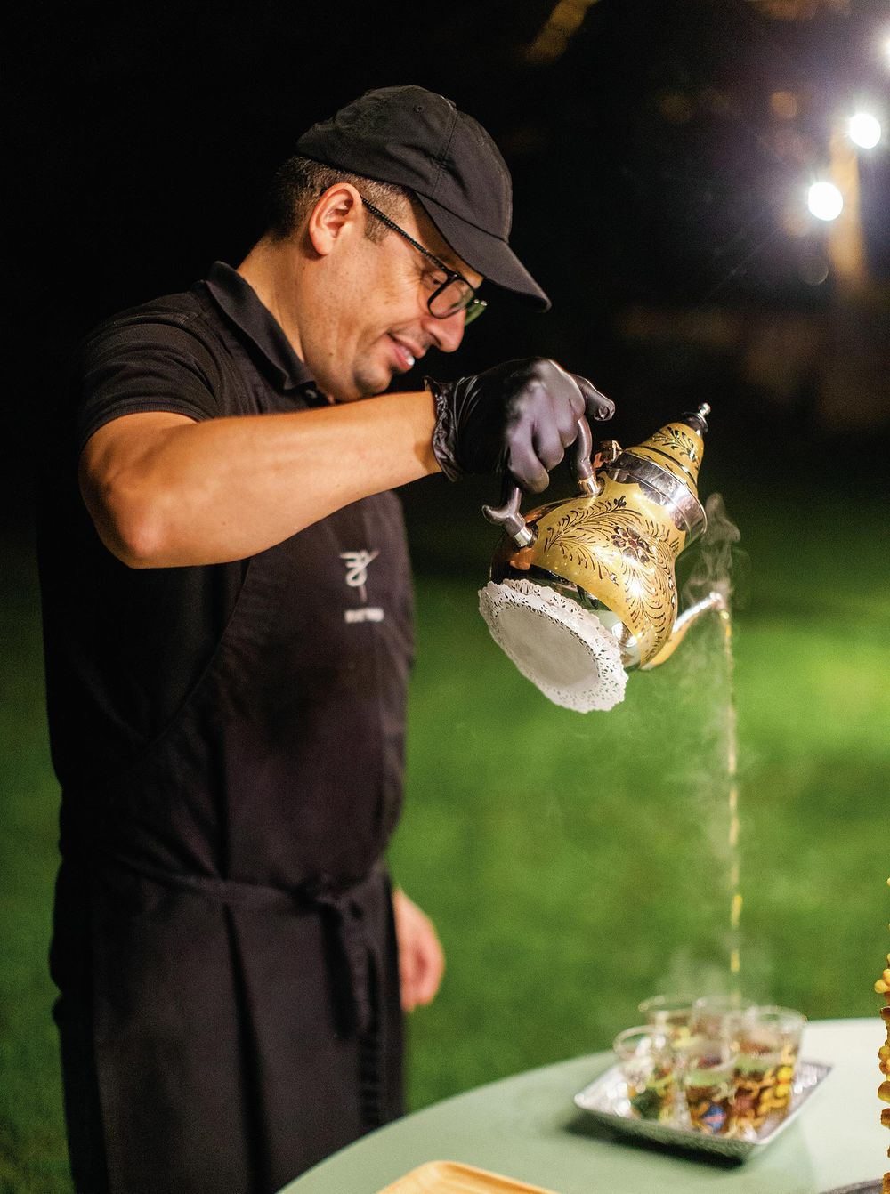 A man carefully pouring Moroccan tea into a cup, showcasing the art of tea preparation.