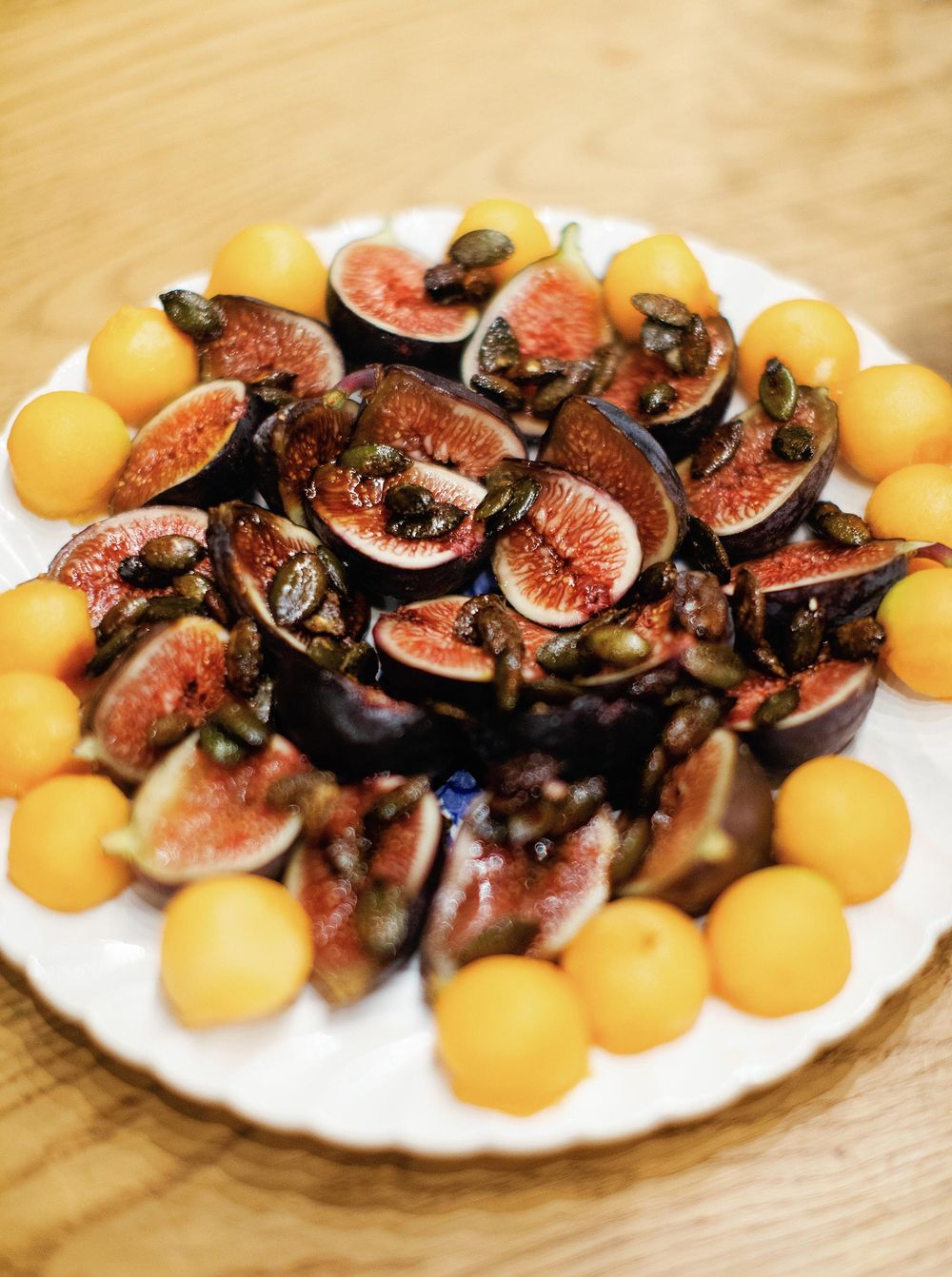 A plate of assorted fresh fruits and figs beautifully arranged on a table.