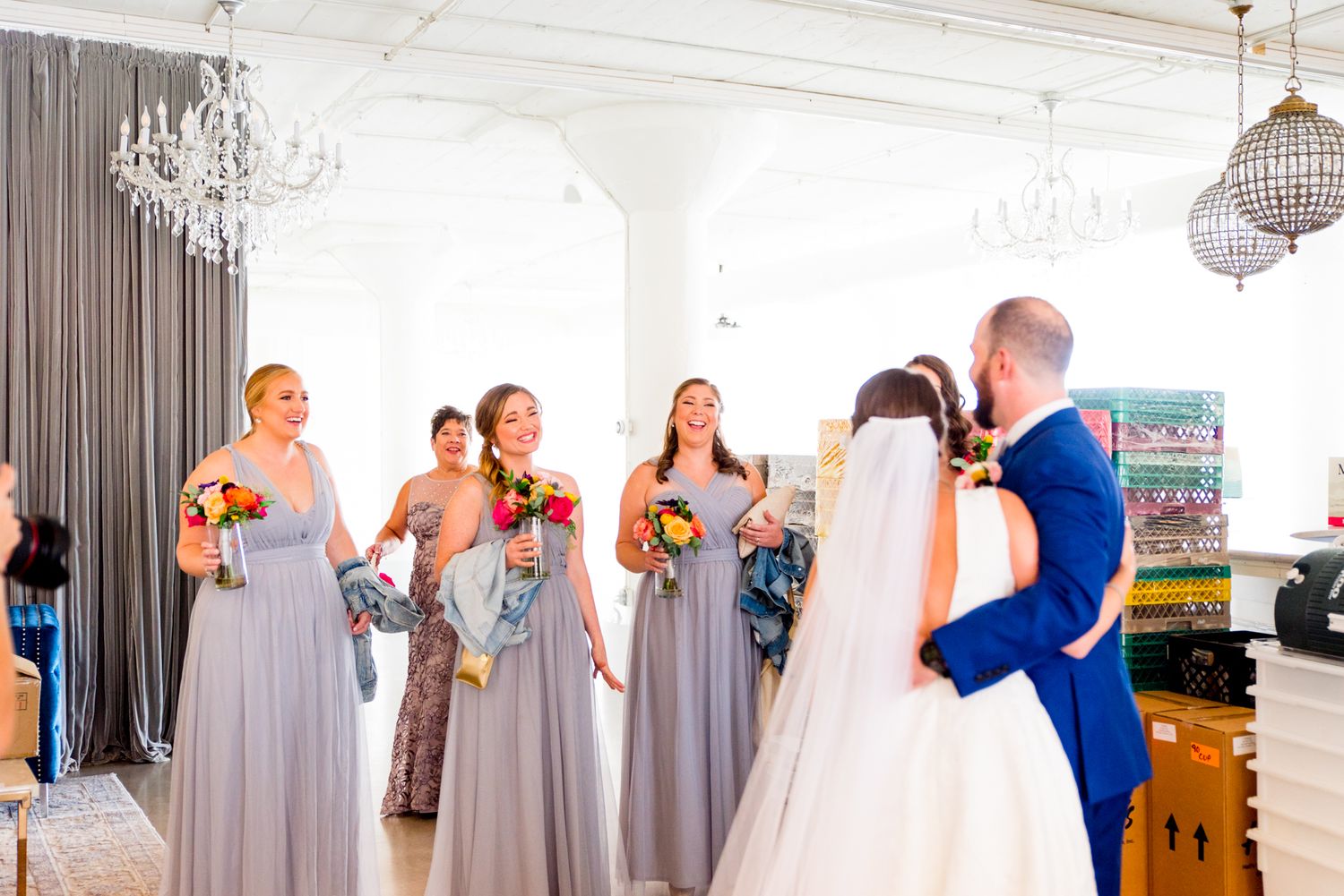 bride and groom stand in front of their smiling wedding party for first look inside Room 1520 wedding in Chicago