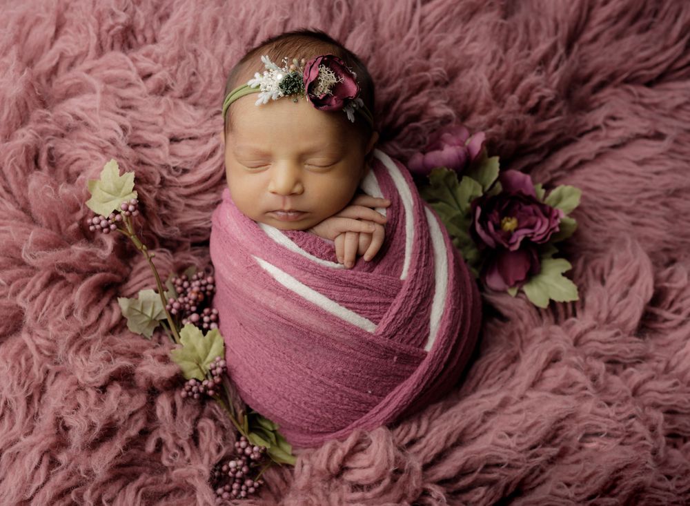 Newborn Photo of baby swaddled in mauve with flowers by austin baby photographer