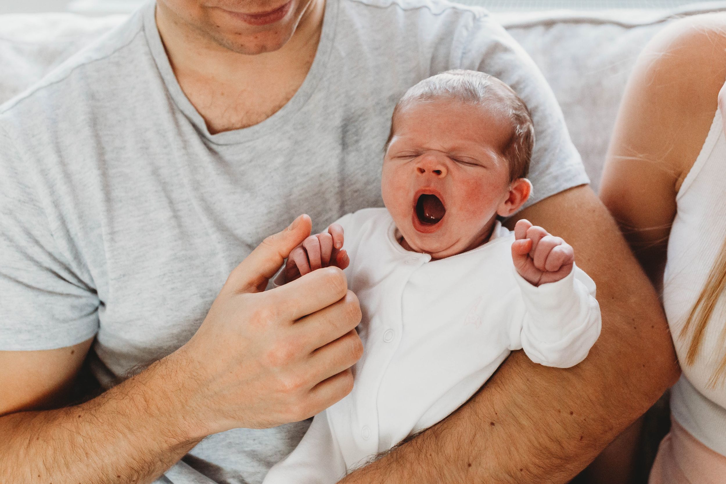 yawning baby girl in white onesie