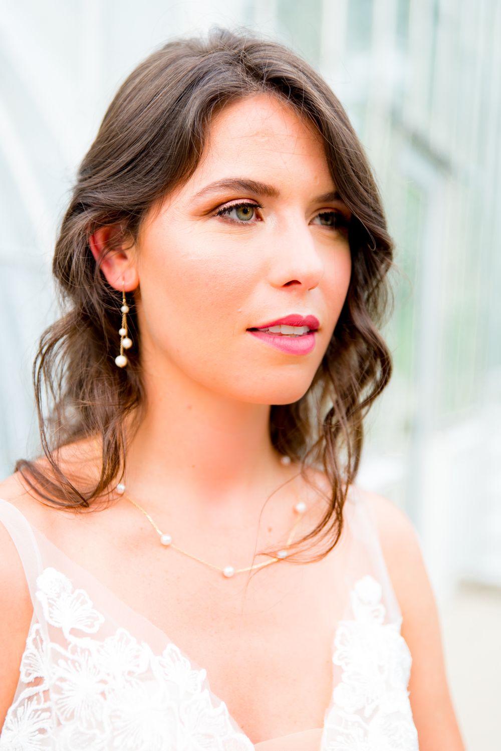 bride in hot pink lipstick, gold and pearl dangle earrings, and pearl and gold necklace stares off to the side at Krohn