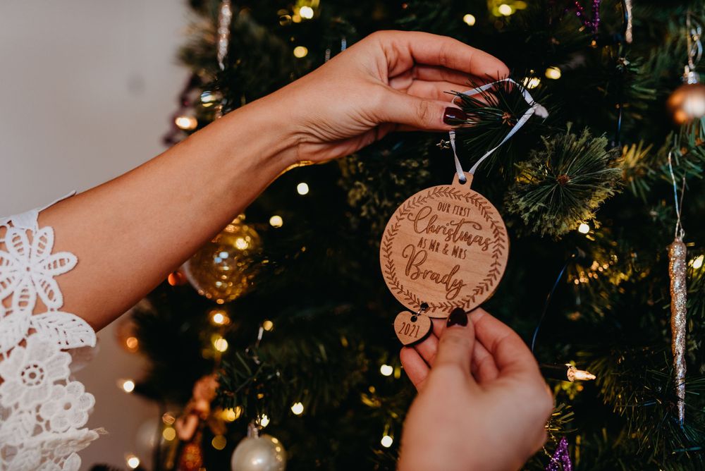 A Christmas wedding with the bride placing a personalised decoration on her Christmas tree saying 'Our First Christmas'.
