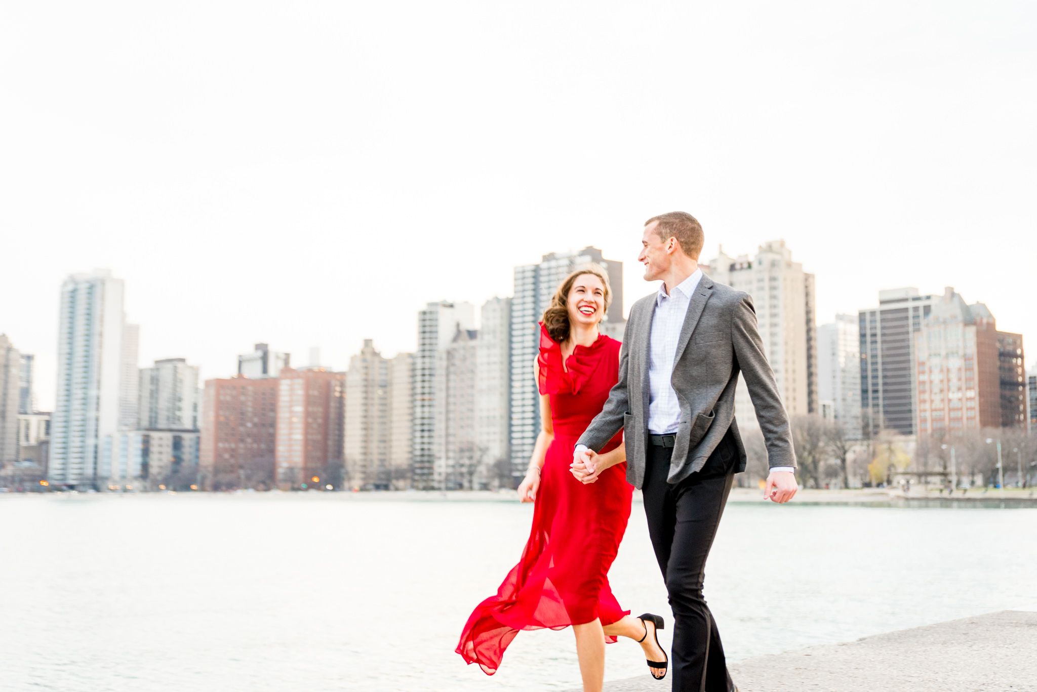 couple running along pier at North Avenue Beach for Chicago engagement pictures