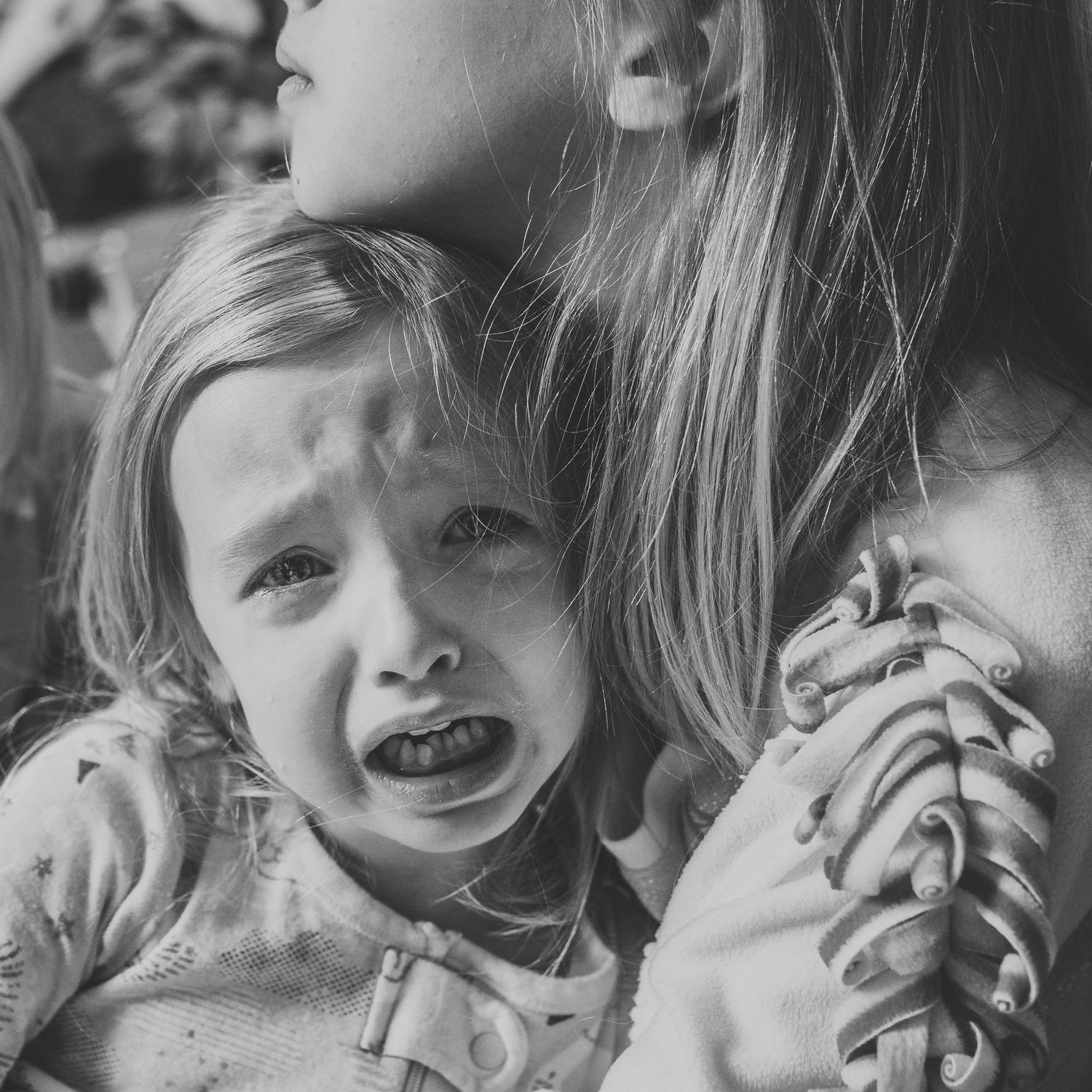 Little girl who is crying is comforted by her older sister