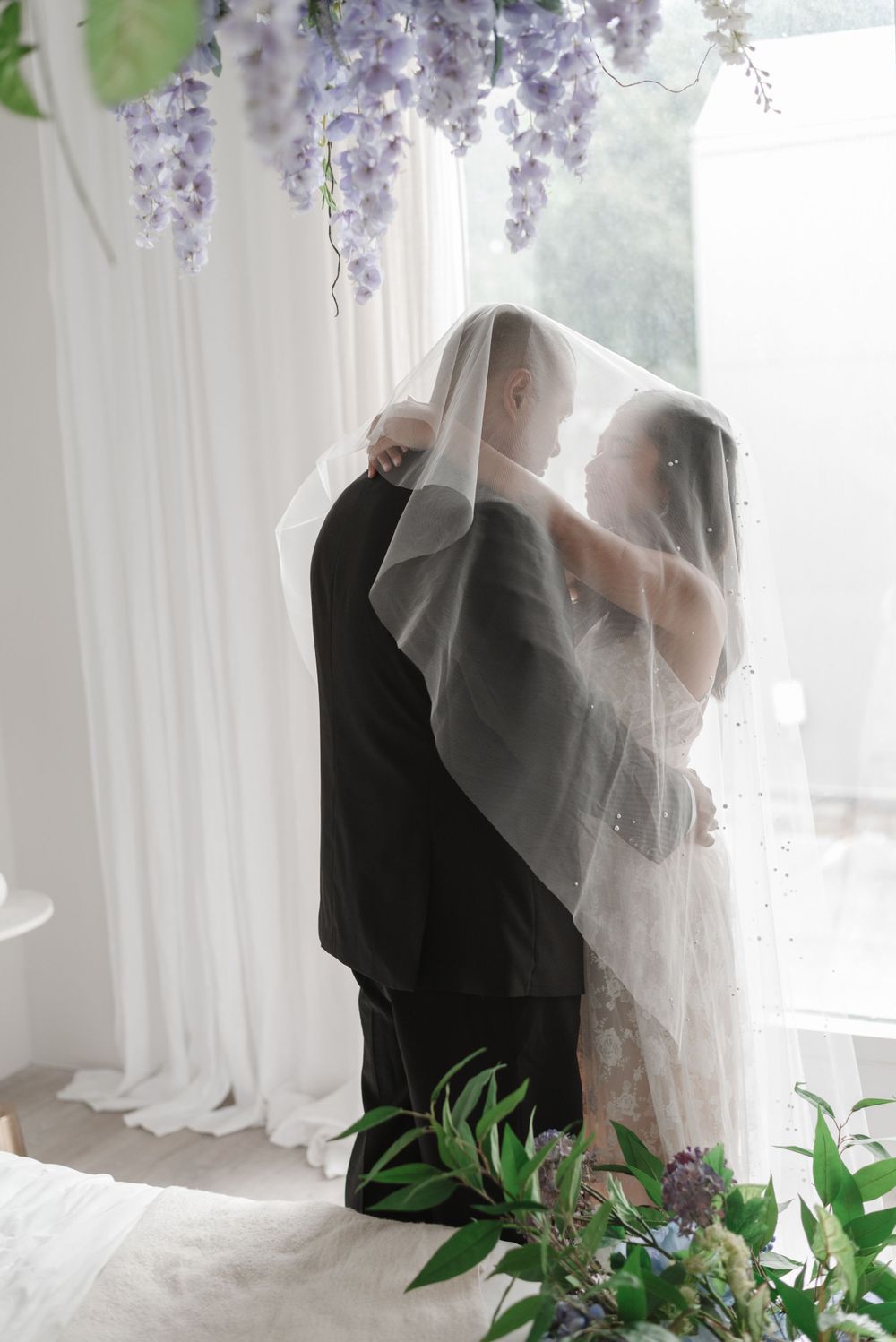 Bride and groom posing together at Toronto's Mint Room Studios before wedding ceremony, dressed in elegant wedding attire, under a veil