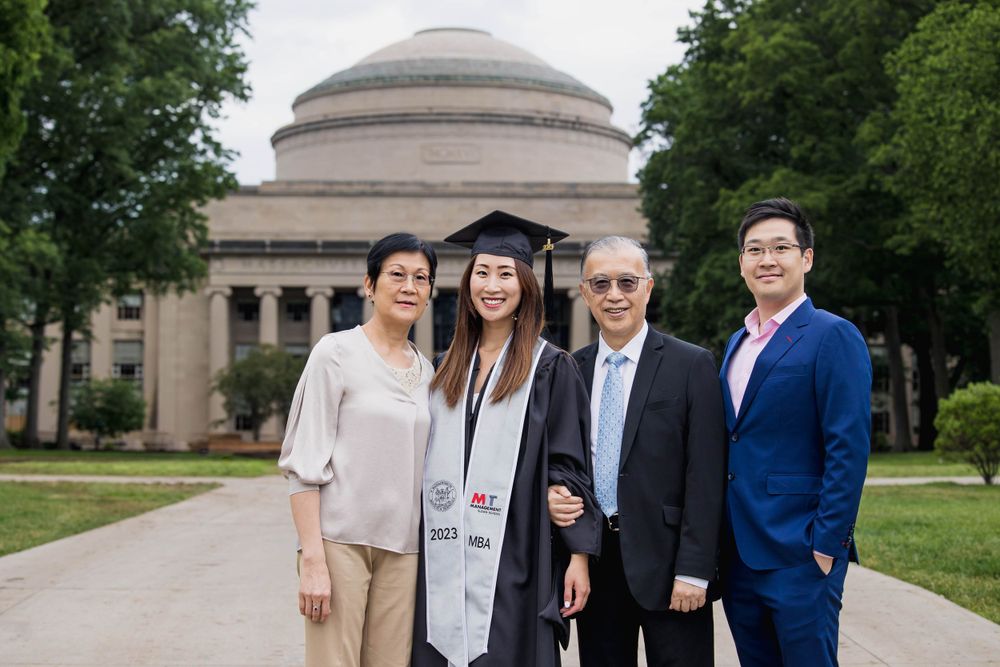 Family poses along pathway leading to MIT's iconic dome building during graduation.