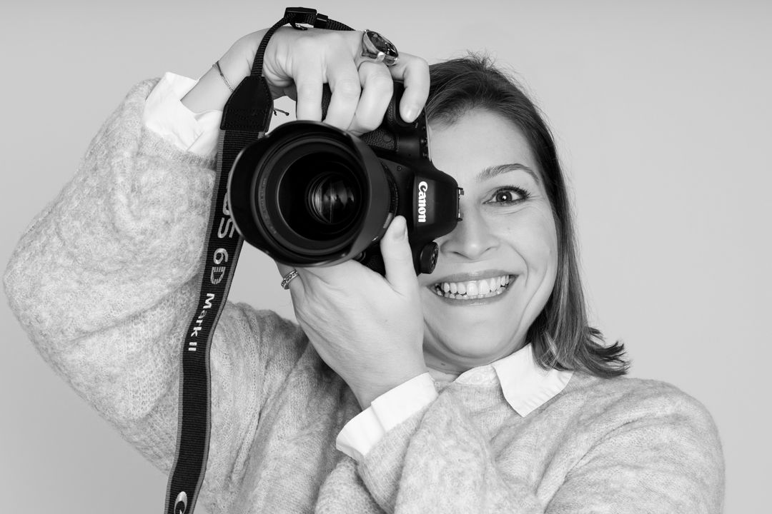 Black and white portrait of photographer holding professional camera.