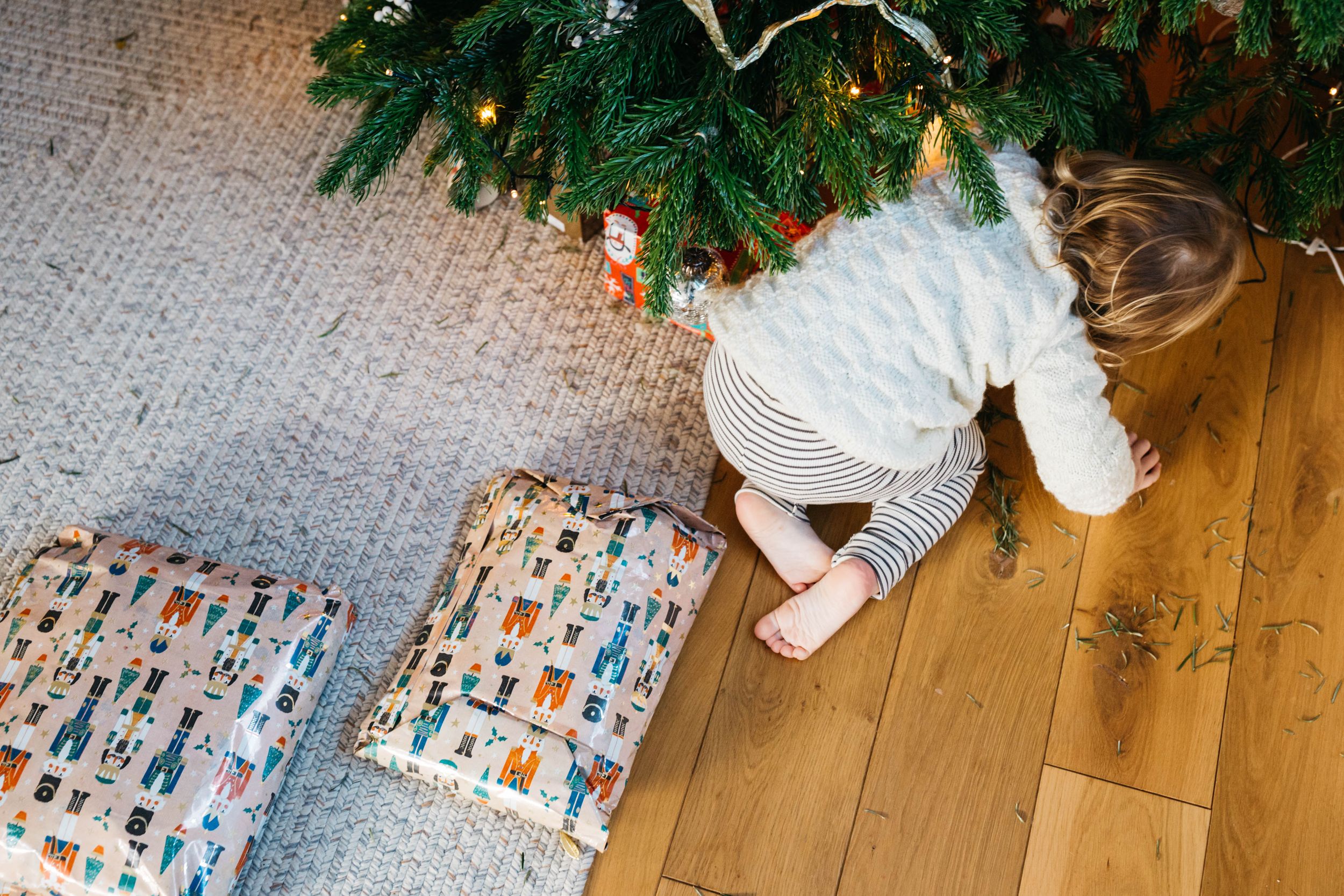 boy looking for presents under Christmas tree