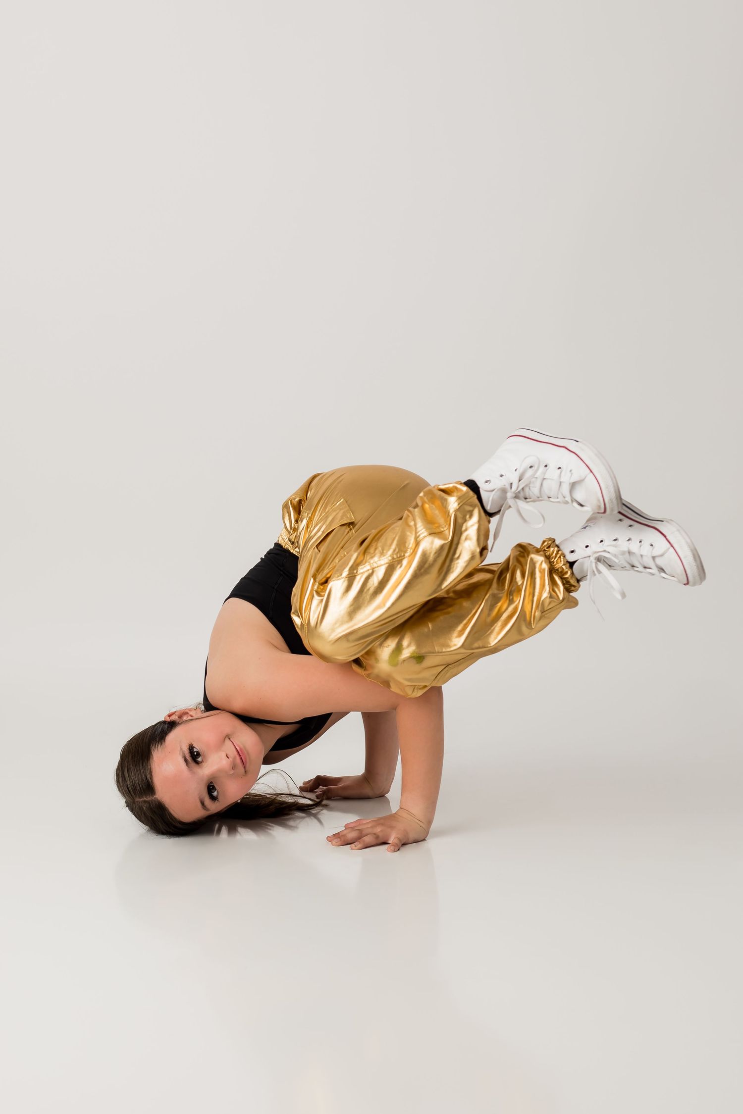 Hip hop dancer busting a dance move for her dance portrait session on a plain white background.