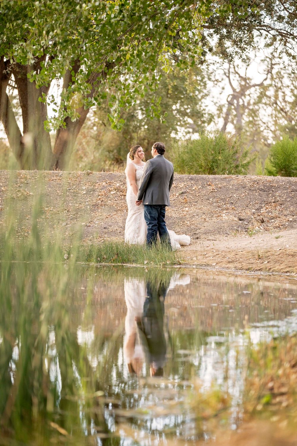 Bride and groom looking at each other with their reflection on the water at Fallen Oaks Estate