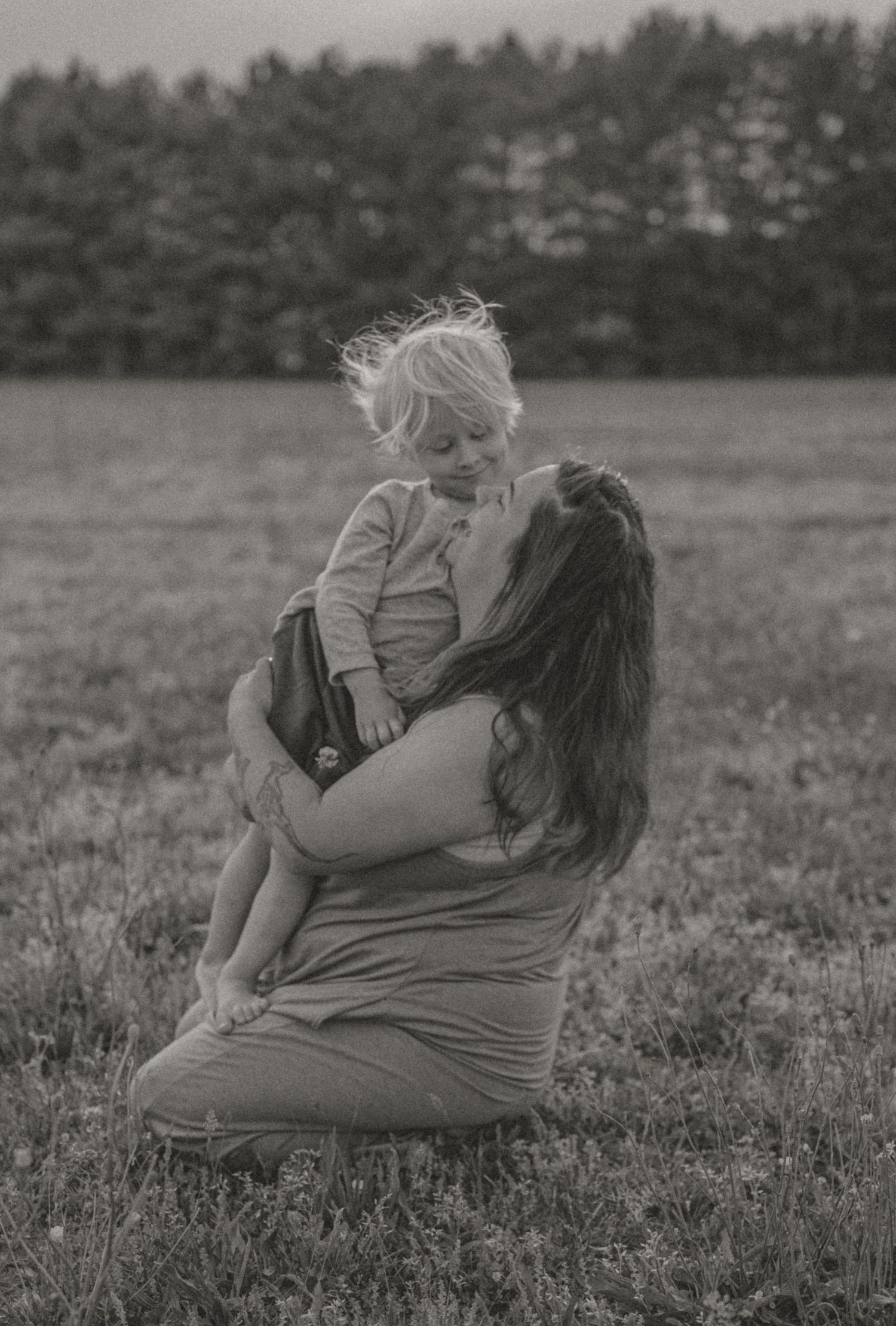 A tender moment between parent and child captured in black and white in a grassy field. photo by Samantha Campbell imagery