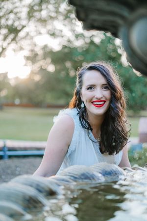 Photo of Jenni looking through a fountain to smile at the camera.