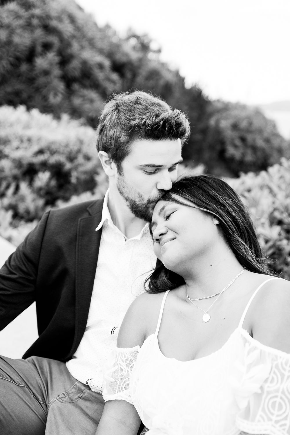 black and white image man kissing woman on her forehead with eyes closed for San Francisco engagement pictures