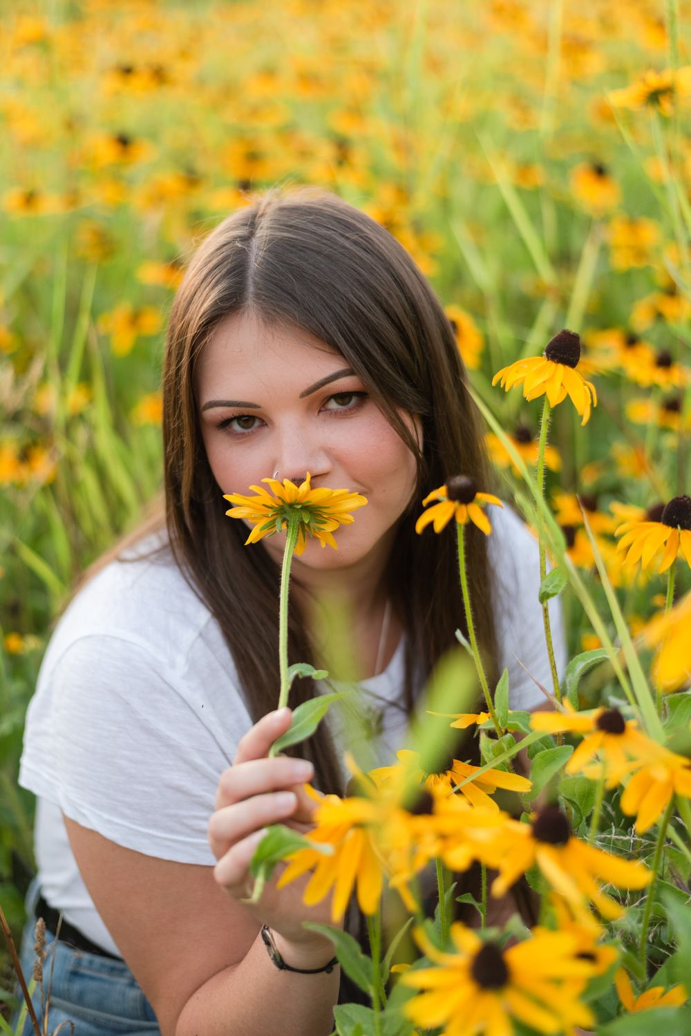 High school senior sitting in flower patch in golden sunlight at Hartwood Acres in Pittsburgh Pennsylvania