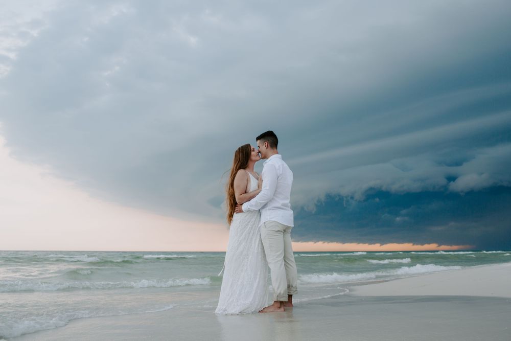 man and woman standing facing each and giving each other a kiss on the beach during their elopement