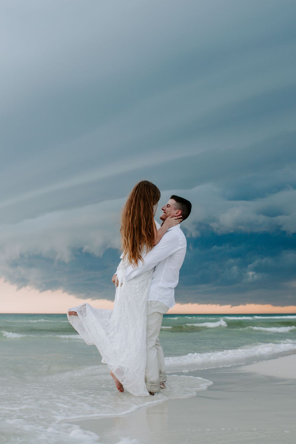 man picking up his new wife as she holds his face during their Florida elopement