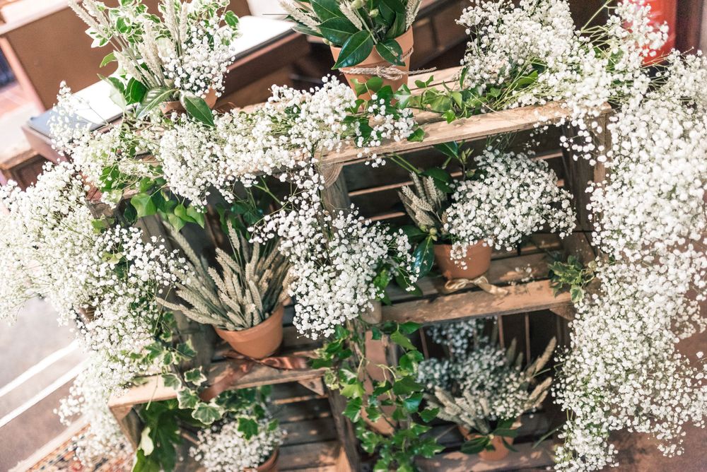 Decorative wedding arrangement featuring baby's breath flowers on wooden display.
