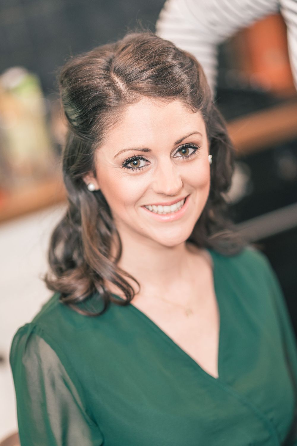 Portrait of someone wearing emerald green top with vintage-inspired hairstyle.