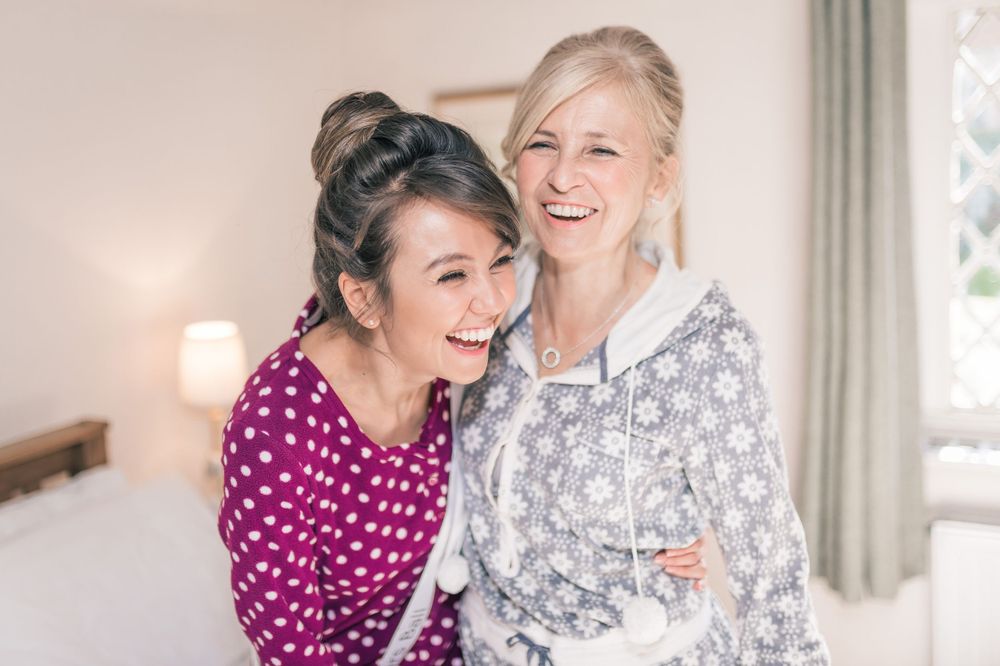 Two friends laughing together while wearing cozy polka dot and floral print pajamas.