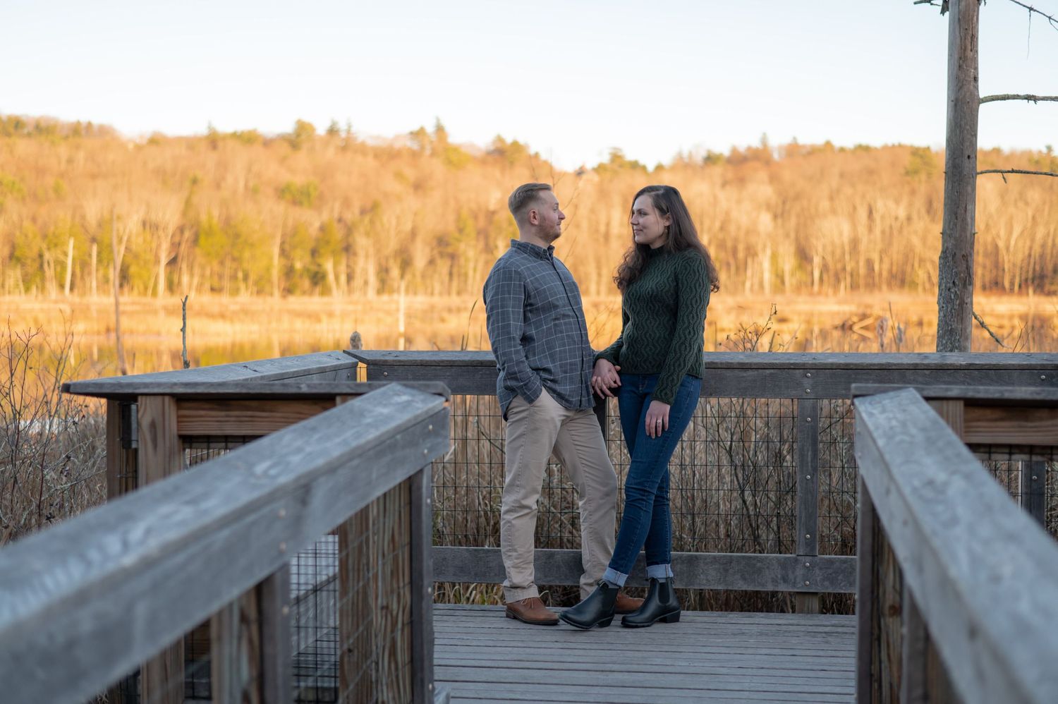 Couple sharing a moment together on a wooden boardwalk at sunset.