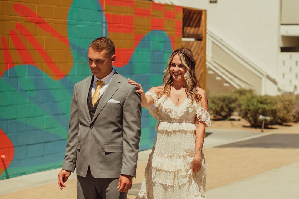 Bride tapping her groom on the shoulder to surprise him with a first look
