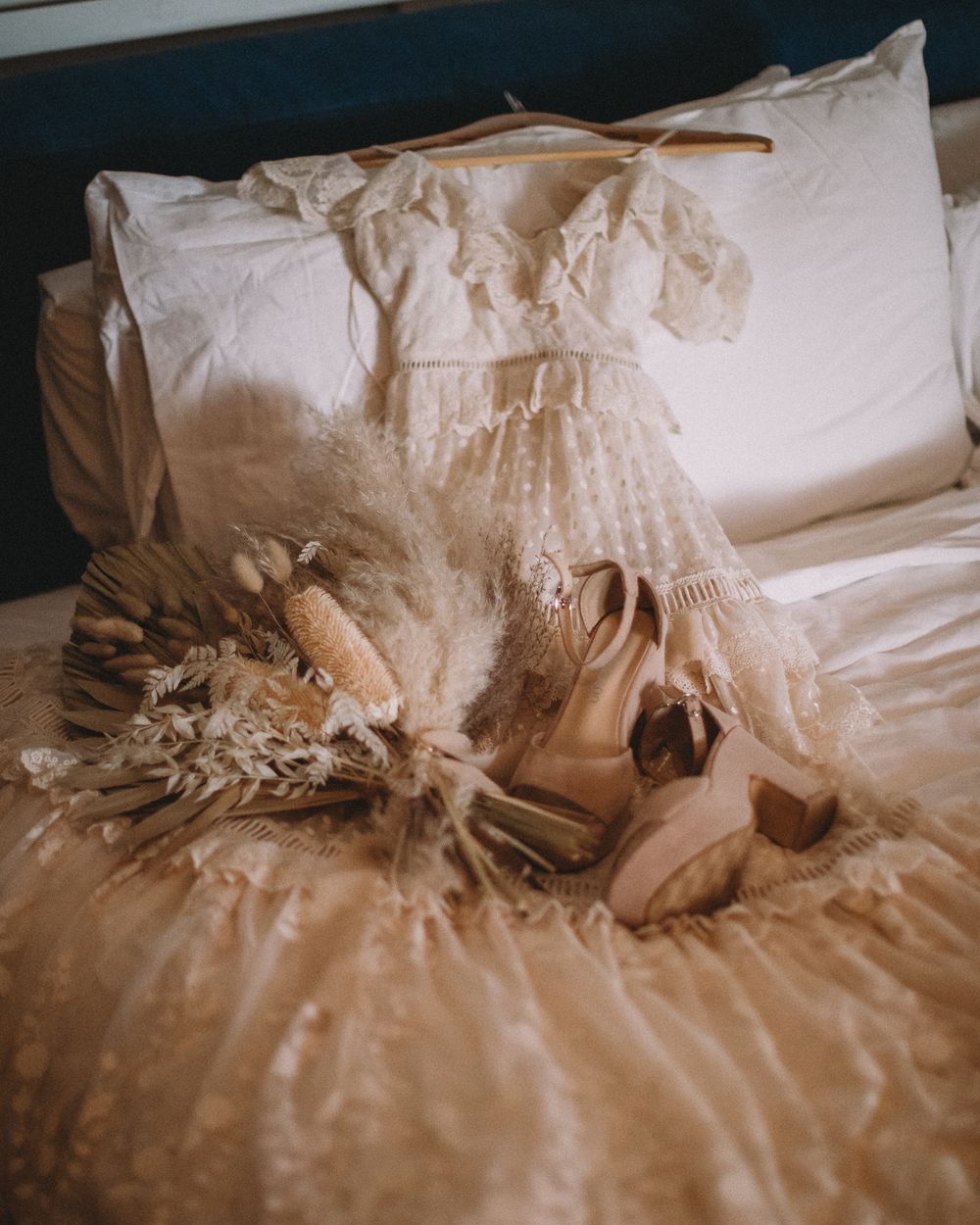 A vintage style wedding dress, bouquet and beige heels arranged on a bed at the ACE Hotel in Palm Springs