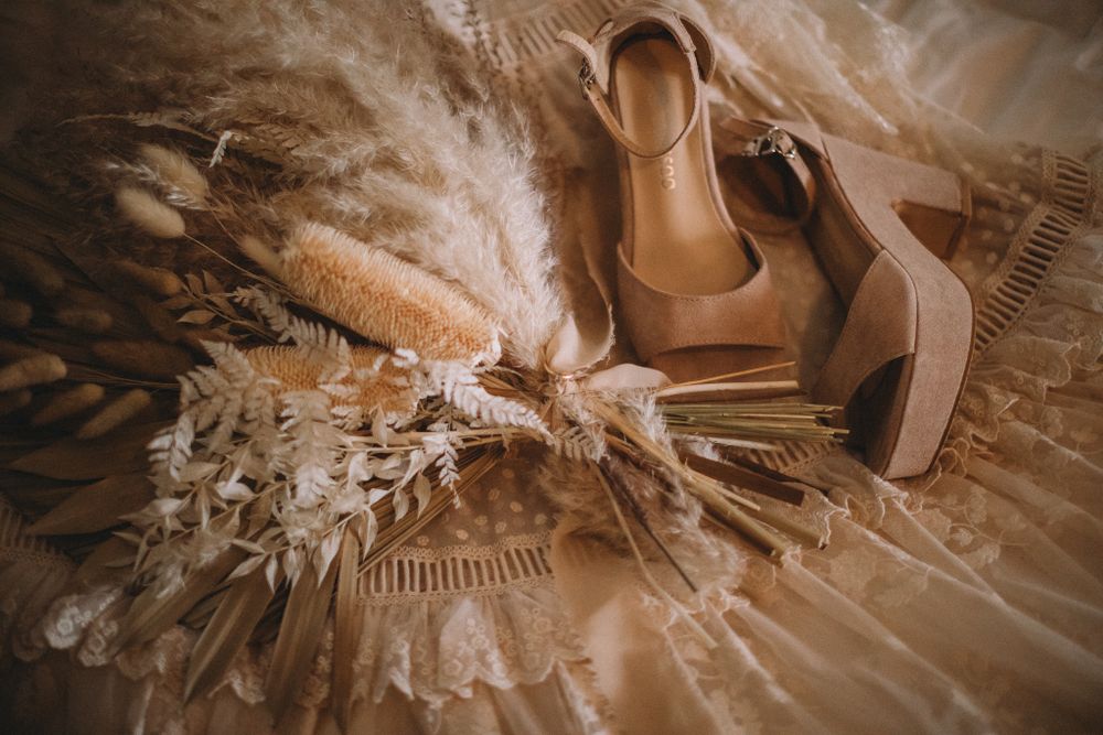 Flat lay wedding photography of brides shoes, dress and bouquet