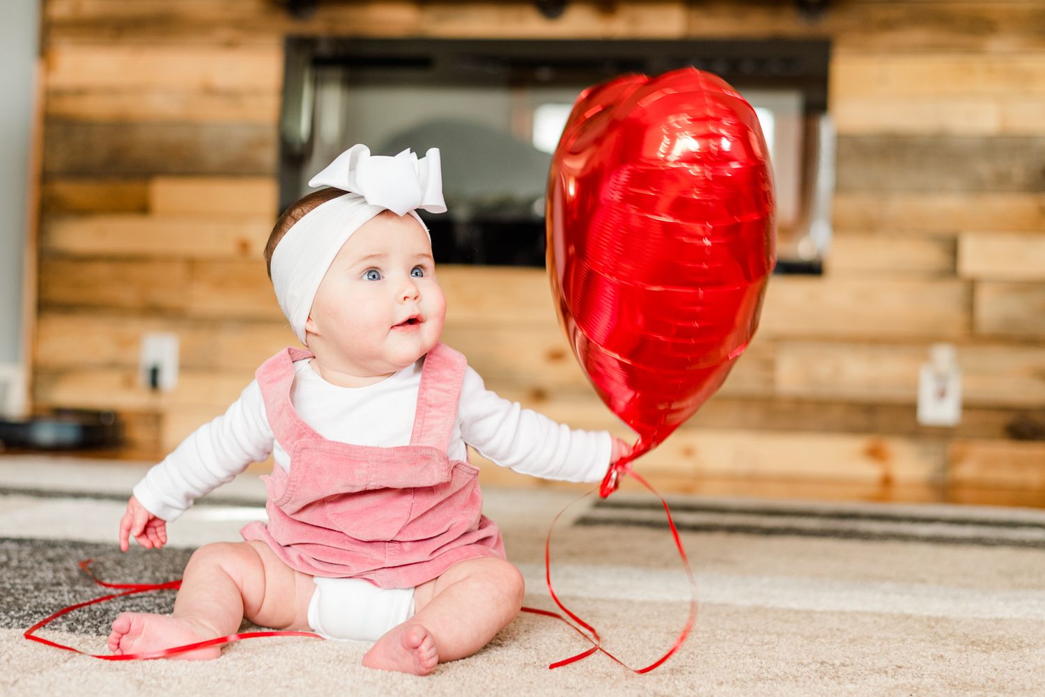 Lifestyle family photoshoot in the home with 6 month old baby holding a heart balloon in Gibsonia, Pennsylvania